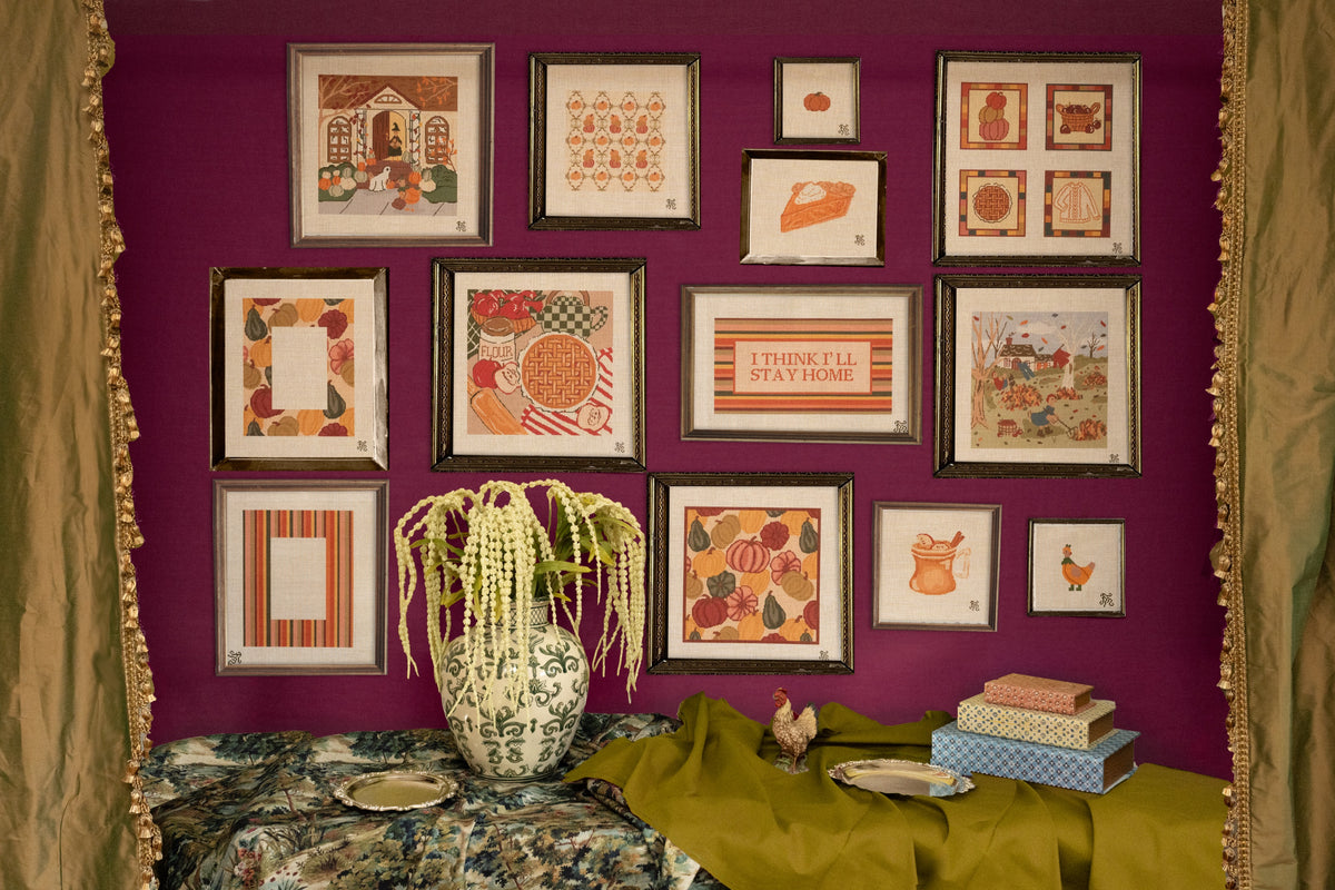 Finished fall needlepoint canvases framed on a wall